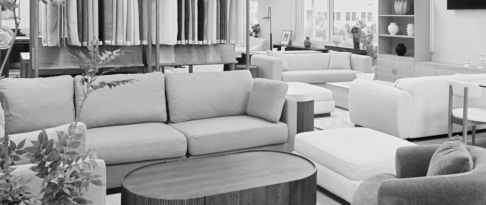 A designer showing a customer a furniture piece and material sample in a styled showroom