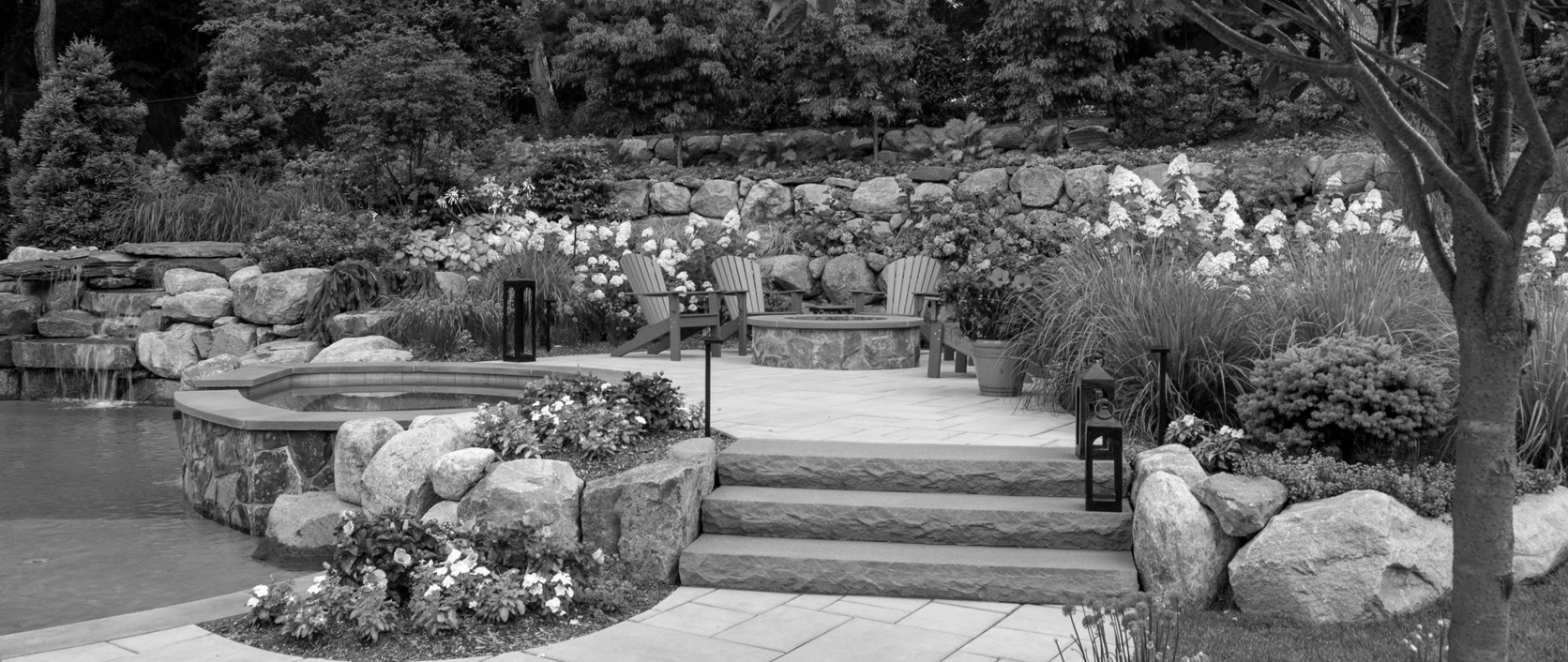 A finished backyard landscape project with a pool, patio and layered planting