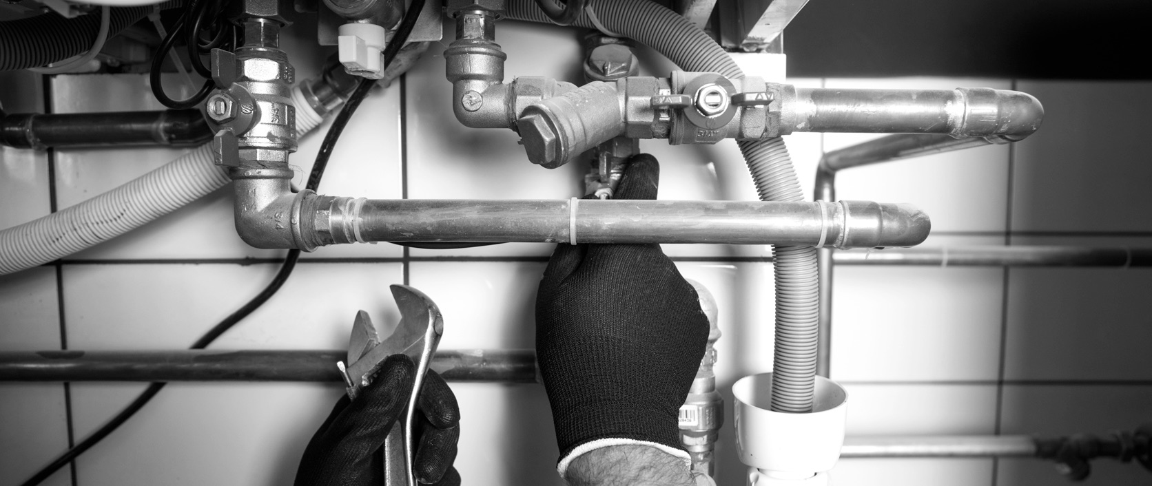 A plumber repairing pipes and valves under a sink