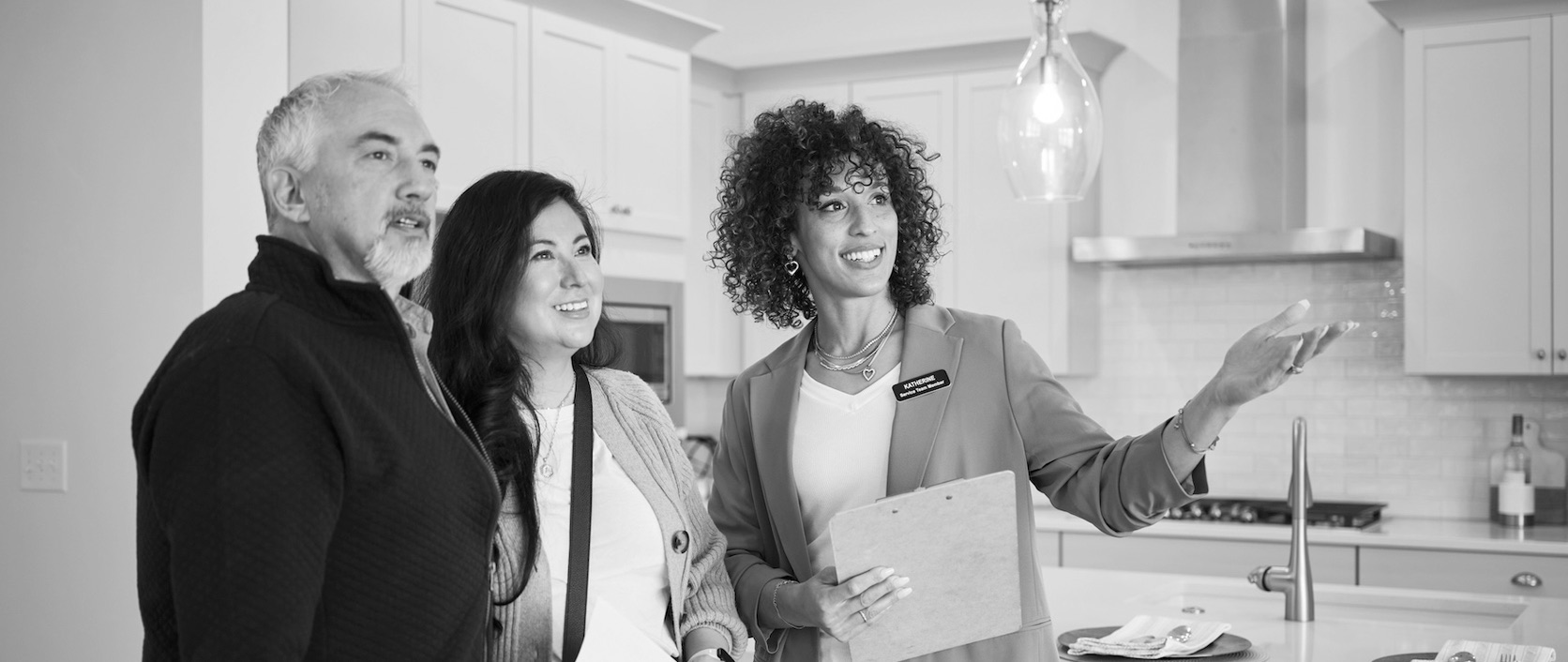 A real estate agent walking a client through neighborhood options at a kitchen island