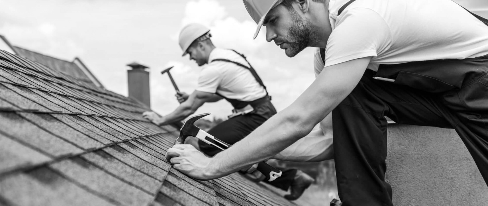 Two roofers installing shingles on a residential roof