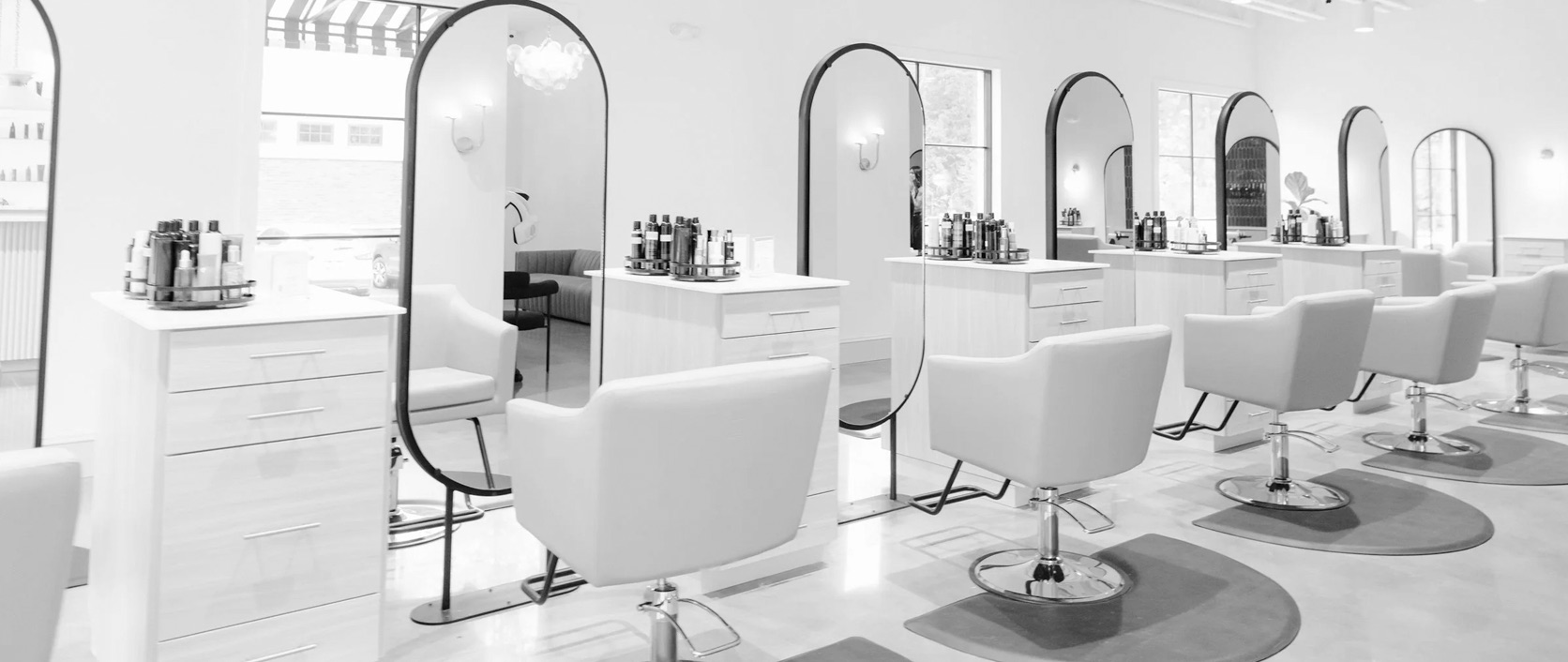 A modern salon with a row of styling stations, mirrors and natural light